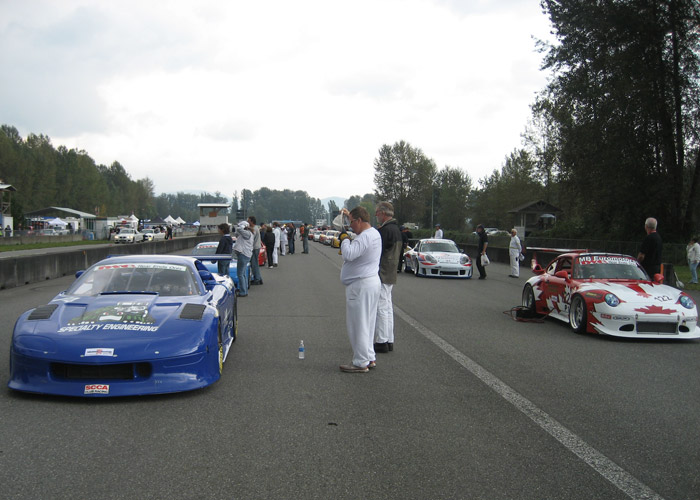 people gather around cars ready prior to the race starting