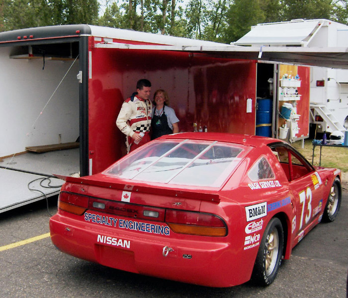 Dave Humphrey with his wife Stephanie Humphrey standing by the red Nissan 240SX racing car